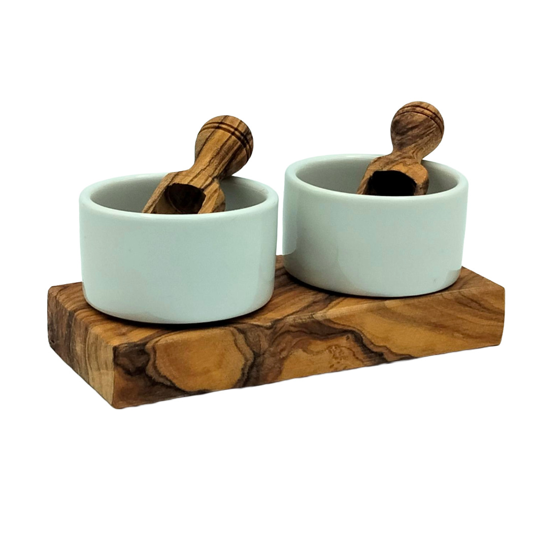 Zwei weiße Keramikschalen mit Holzlöffeln auf einem Holzbrett, ideal für Gewürze oder Dips.