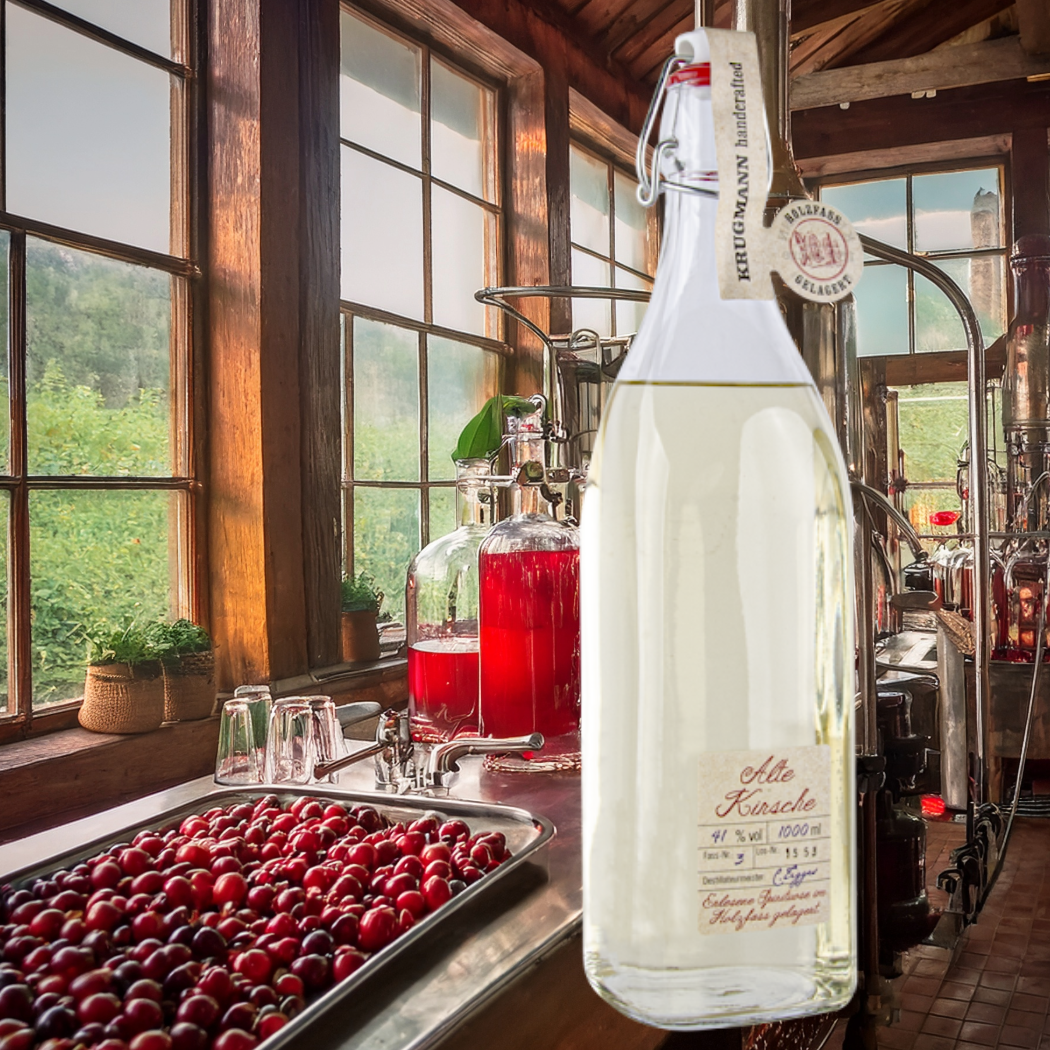 Flasche Alte Kirsche, 41% vol, 1000 ml, klare Flüssigkeit, handgefertigt, im Hintergrund Kirschsaft.