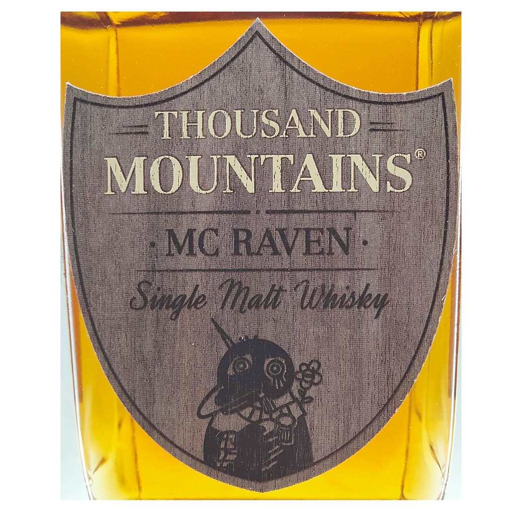 Thousand Mountains MC Raven Single Malt Whisky in einer Glasflasche mit Holzetikett.