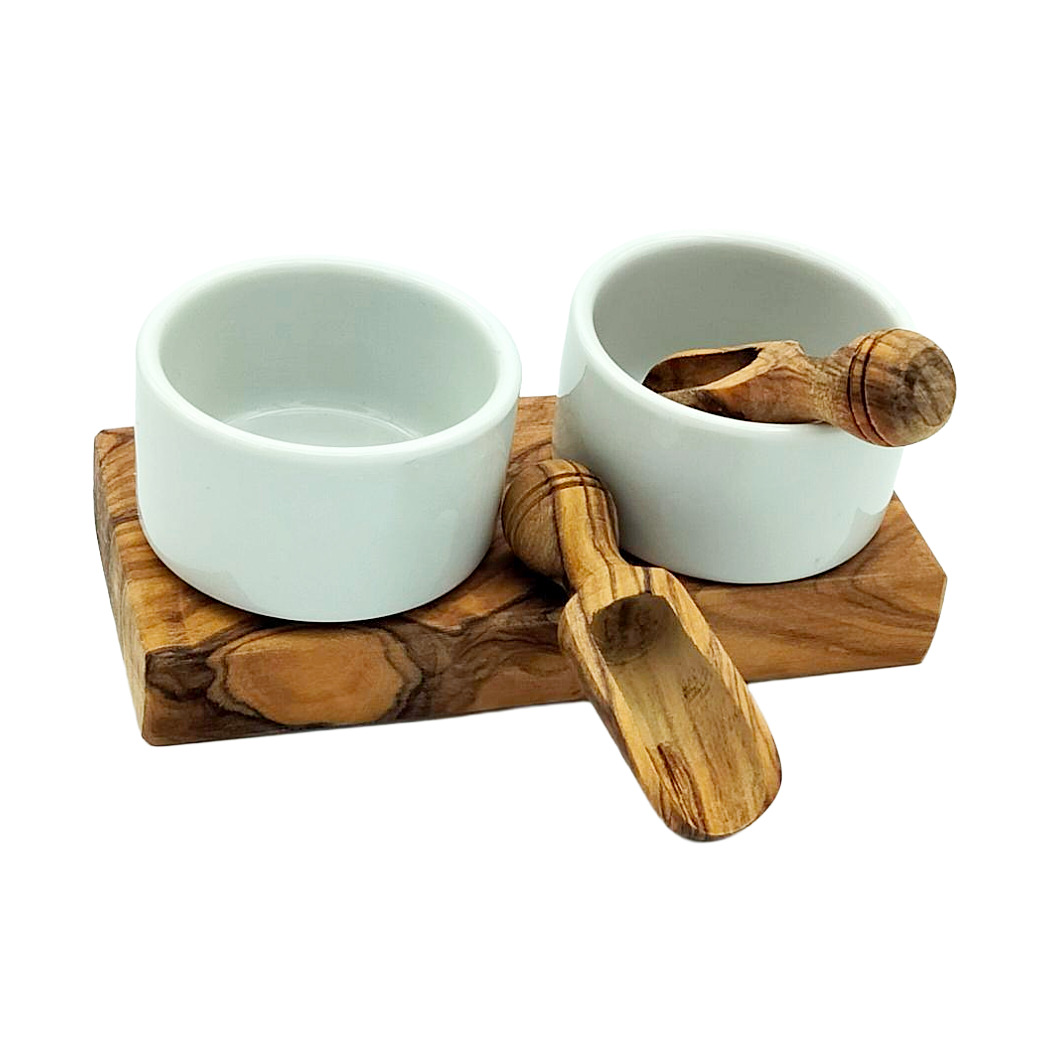 Zwei weiße Keramikschalen auf einem Holzbrett mit einem Holzlöffel, ideal für Snacks oder Dips.