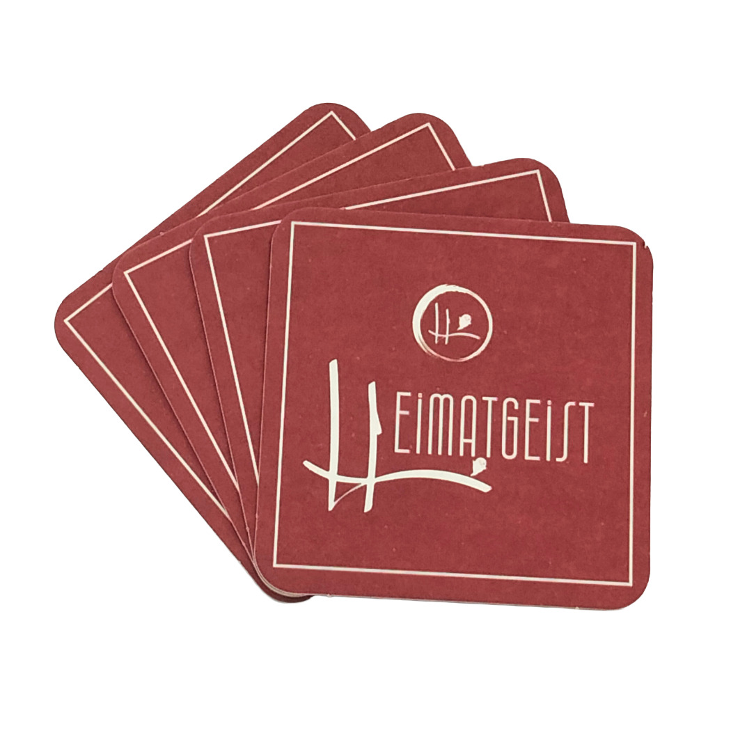 Set aus vier roten Untersetzern mit „Heimatgeist“-Logo, aus strapazierfähigem Material, perfekt für den Heimgebrauch.